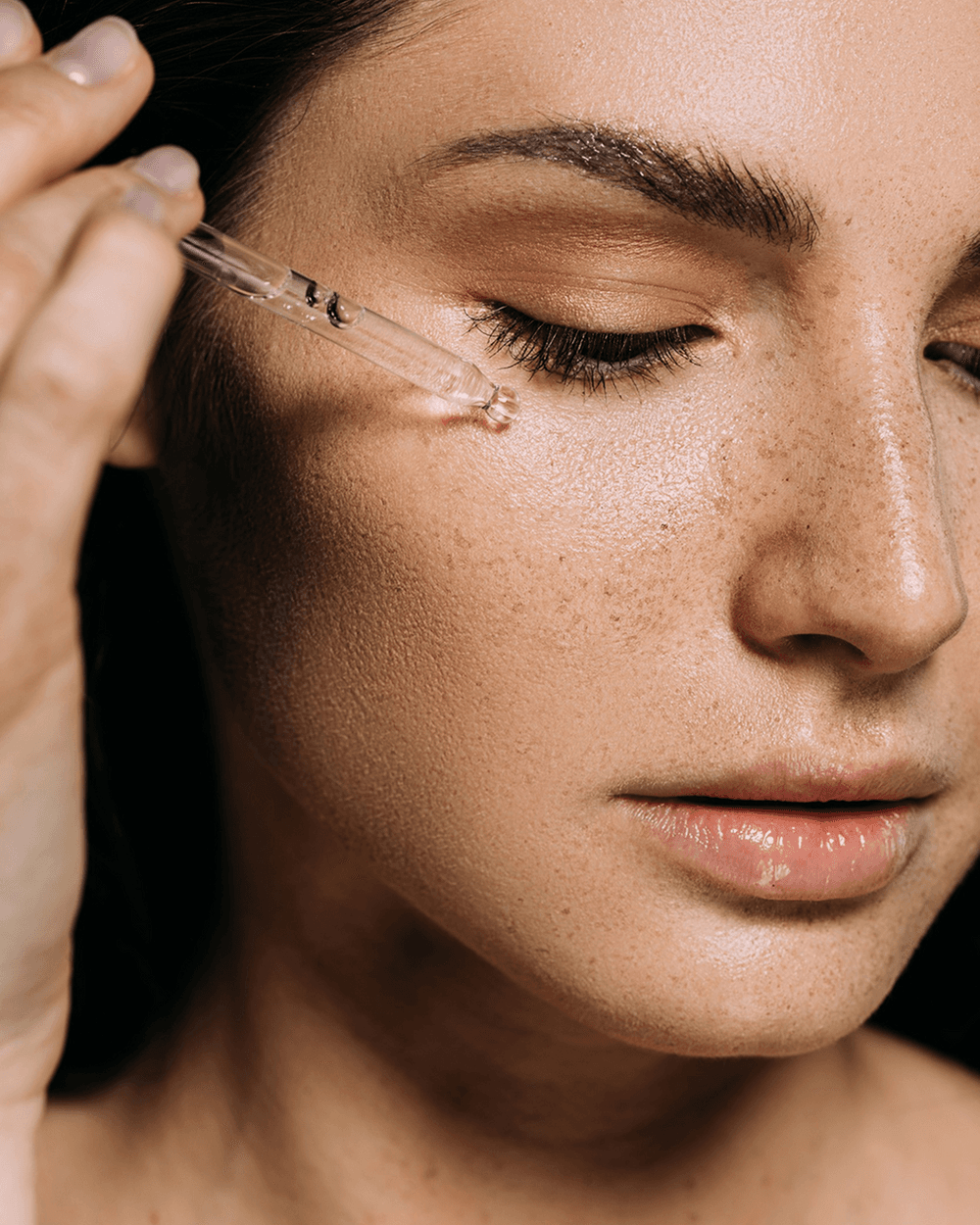 Close-up of a woman applying skincare serum with a dropper, from Rosental Organics.
